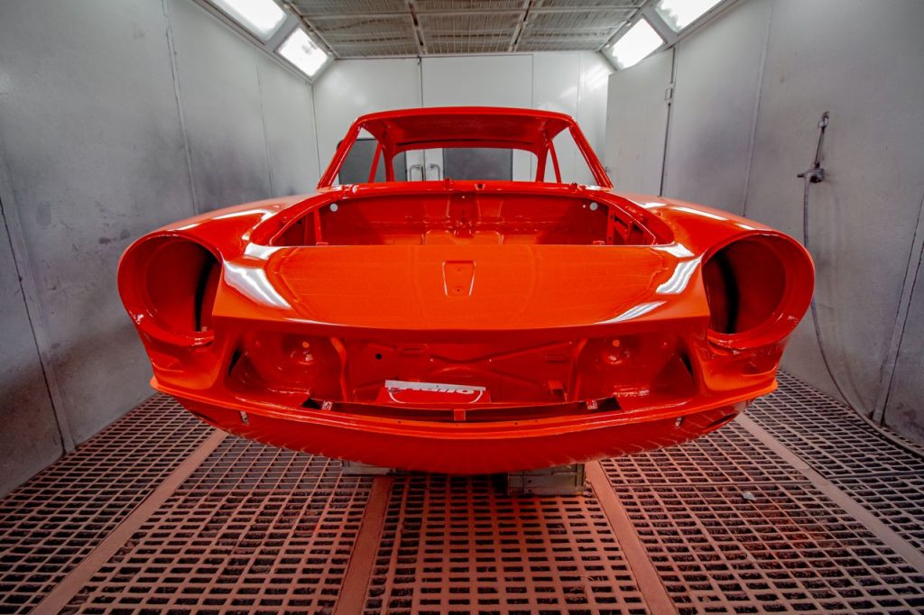 Vividly painted car body in a professional industrial spray paint booth.